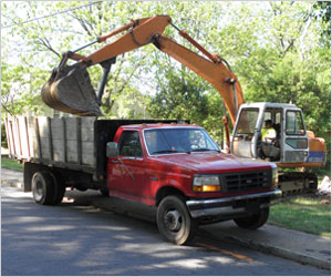 Excavator Loading Debris Into Junk Removal Truck